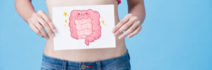 Woman Holding Picture of Smiling Cartoon Intestines Over Stomach Healthy Digestion Concept