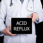 A doctor hold a sign that says "Acid Reflux"