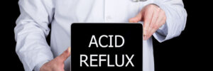 A doctor hold a sign that says "Acid Reflux"