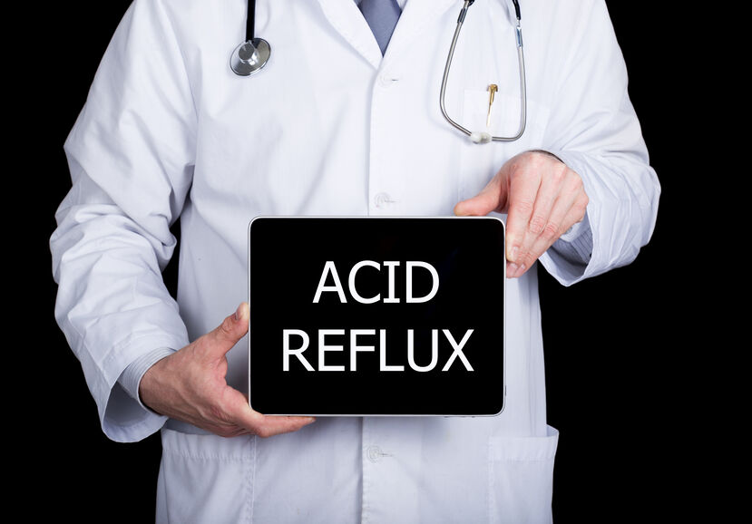 A doctor hold a sign that says "Acid Reflux"