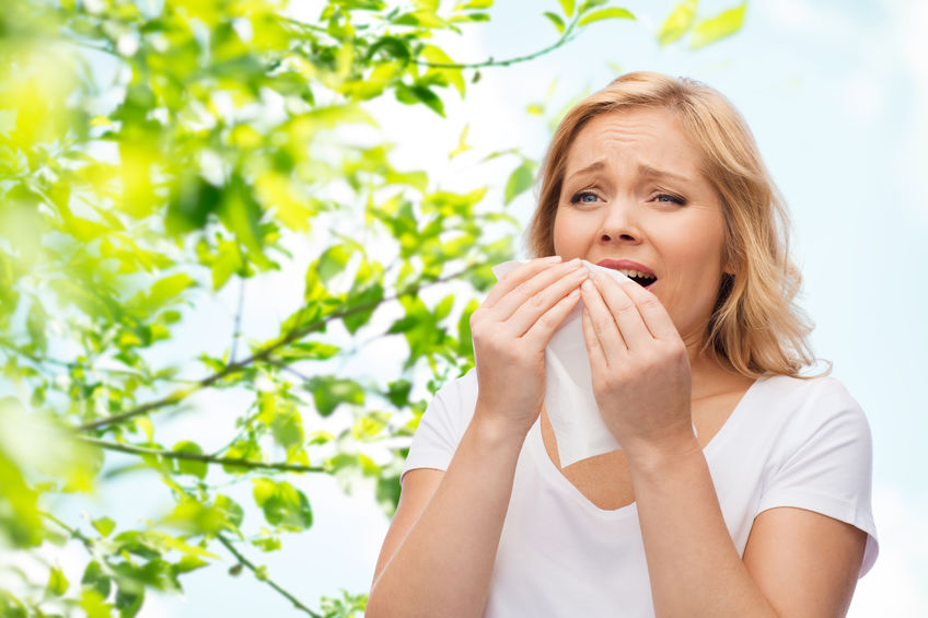 A woman sneezing and suffering from springtime allergies