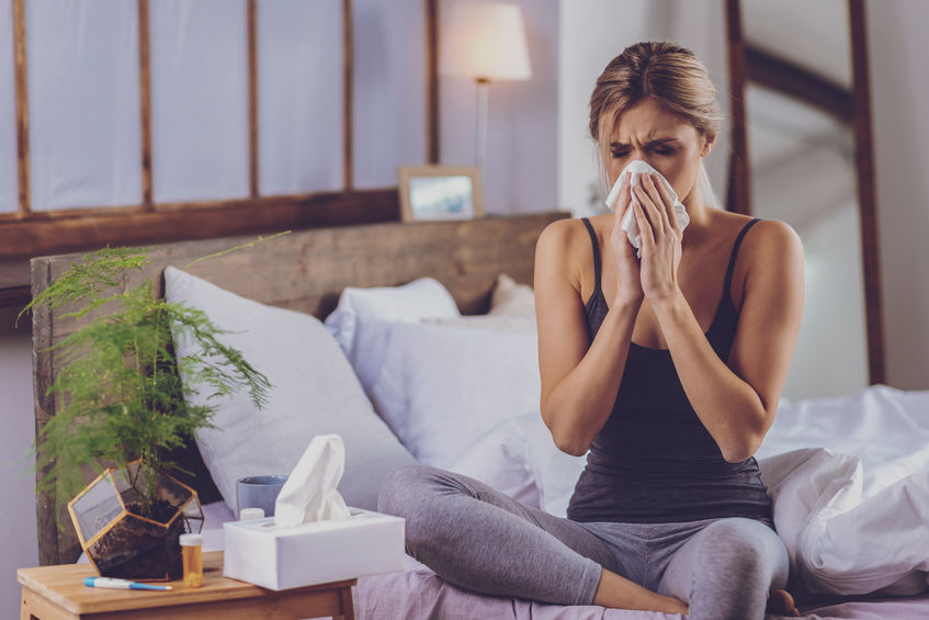 young woman feeling sick with cold & Flu, blowing nose