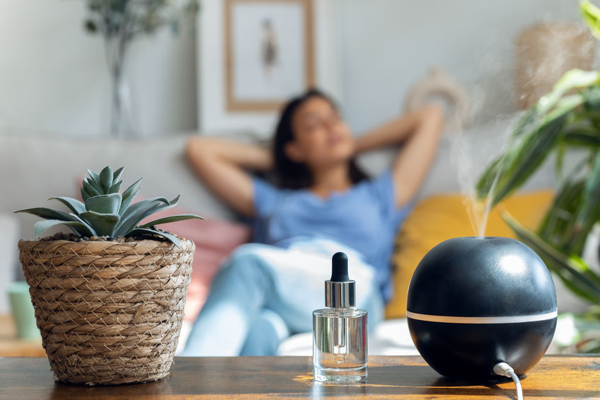 woman relaxing on a coach while essential oil aroma diffuser humidifier the air in living room at home