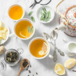 Green tea with lemon, ginger, sage on a light background, top view. Healthy detox drink. Tea ceremony